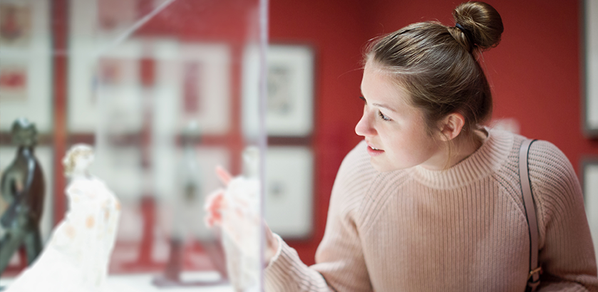 image of a woman looking into a glass museum cabinet