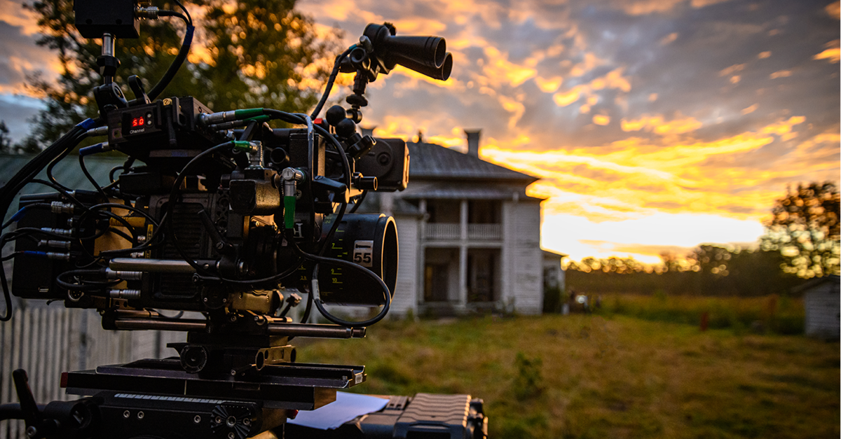 Film camera in front of a country house at sunset.