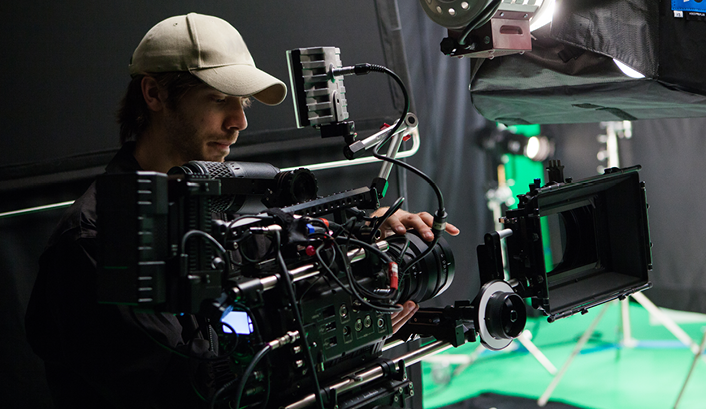 Camera operator standing in film studio in front of camera