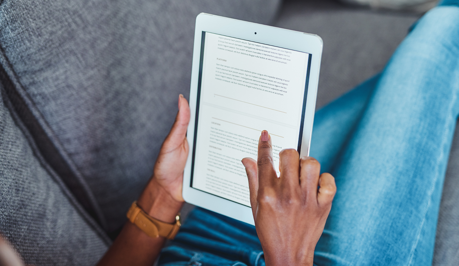 A woman reads an e-book on a couch