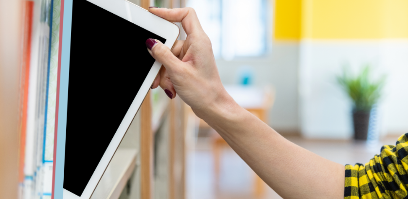 An outstretched hand from the right is pulling an ipad from a bookshelf on the left