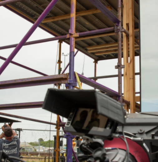 Stunt man hanging from balcony as the film crew record him. 