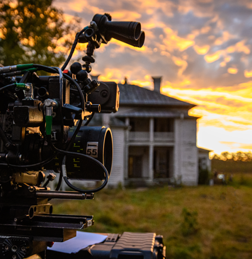 Film camera in front of a country house at sunset.