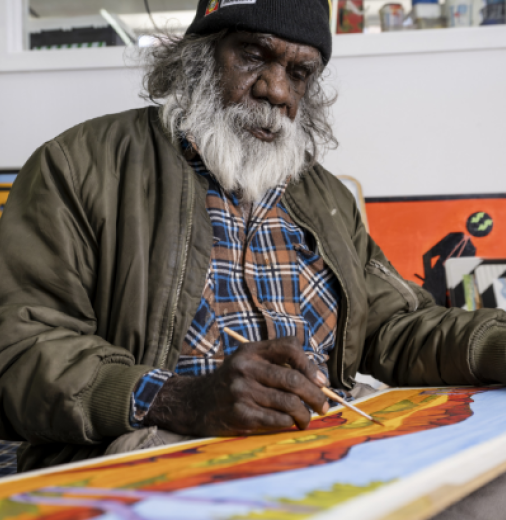 Mervyn Rubuntja 2021, painting in the Iltja Ntjarra Studio. Image courtesy: Shaana McNaught, Tourism NT.