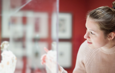 A woman peers into a cabinet with a statue inside.