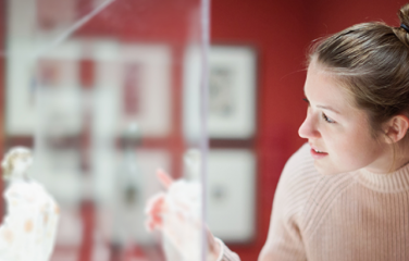 A woman peers into a cabinet with a statue inside. 